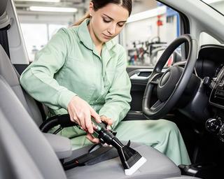 Mitarbeiterin bei der sorgfältigen Innenreinigung eines Fahrzeugs im Waschcenter